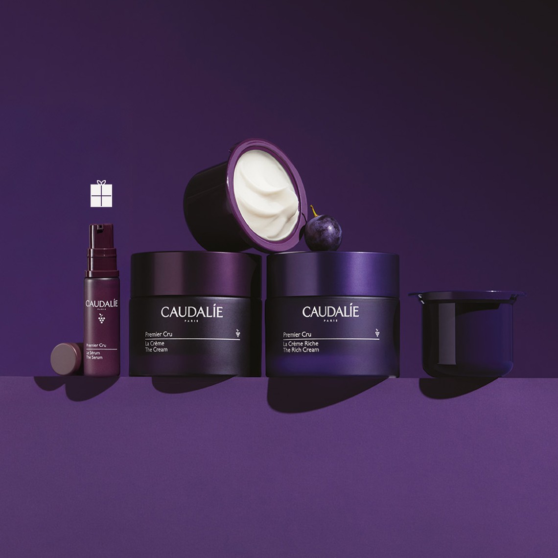 Purple background with skincare and makeup products, including jars, tubes.