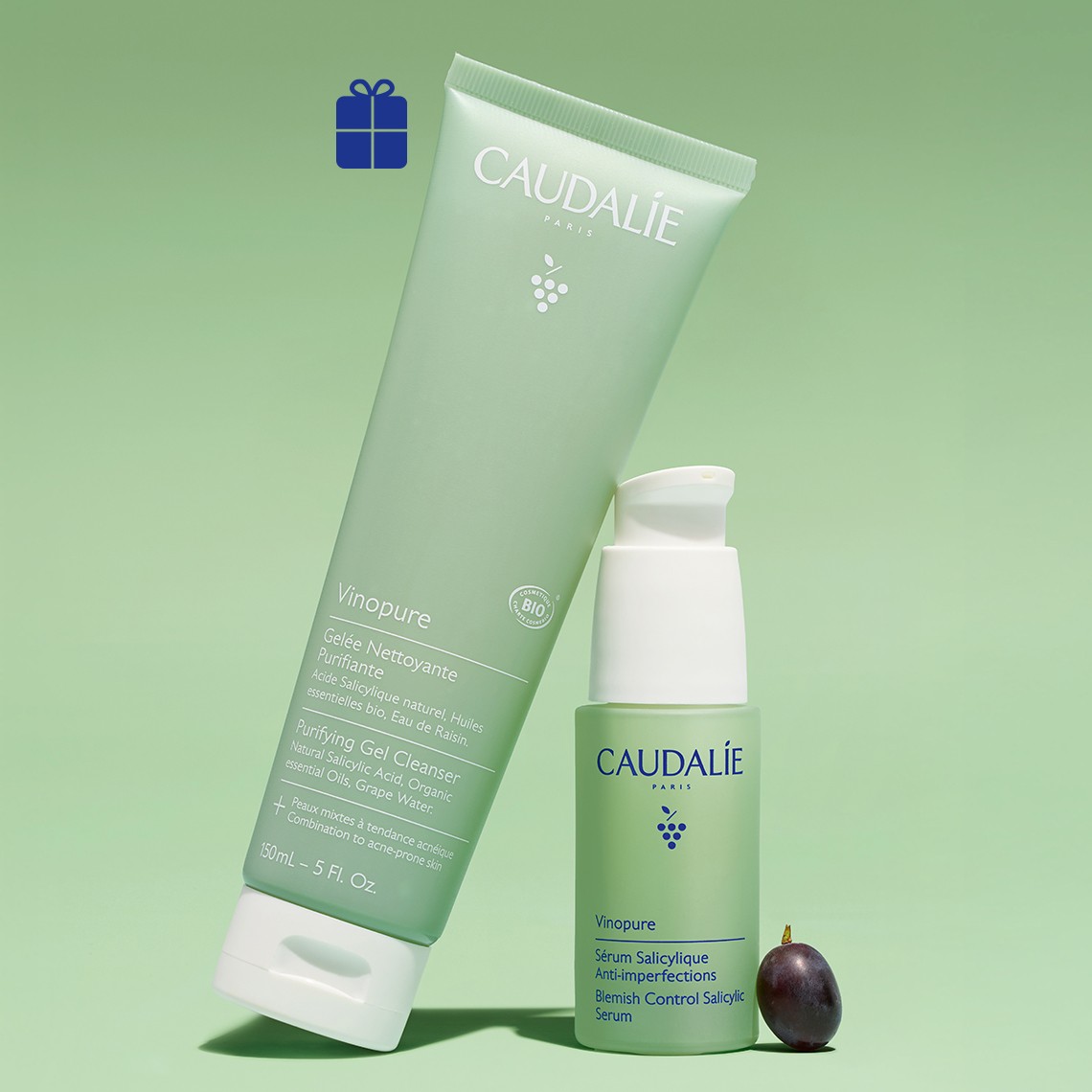 Caudalie Vinopure skincare products including a purifying gel cleanser tube and salicylic serum bottle on green background with gift icon and grape fruit.