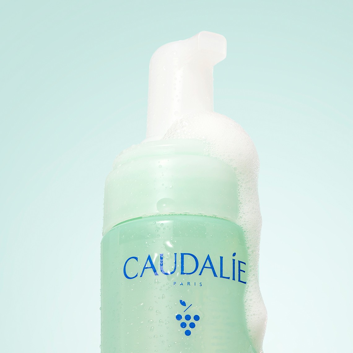 Caudalie Paris foaming skincare product with white foam dispenser against light blue background.
