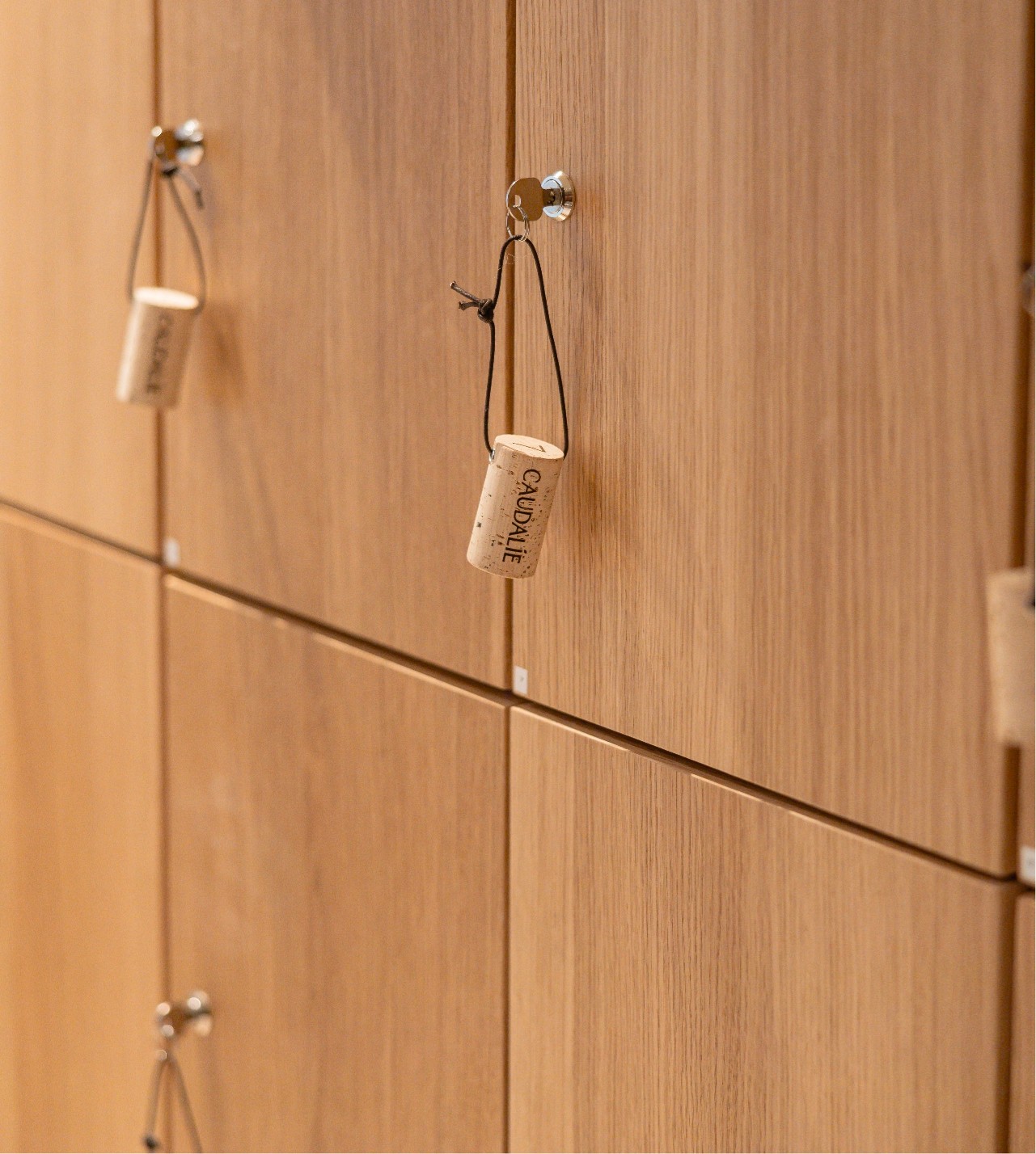 Wooden lockers with cork handles on a wall, each featuring a labeled string for easy opening.