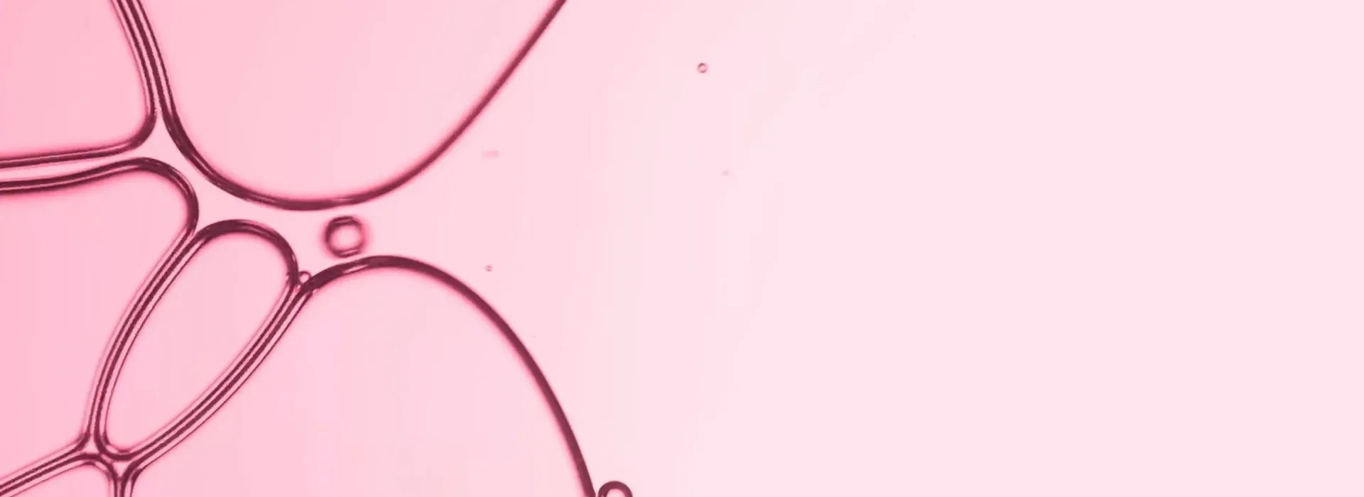 Abstract pink liquid bubbles and flowing streams on a soft pink background creating a minimalist aesthetic composition.