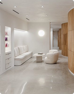 Minimalist interior with white walls, a cushioned bench, a round chair, a small table, built-in shelves, and wooden accents along the hallway.