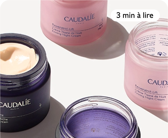 Open jars of Caudalie Resveratrol-Lift Firming Night Cream and another cream, placed on a white surface.