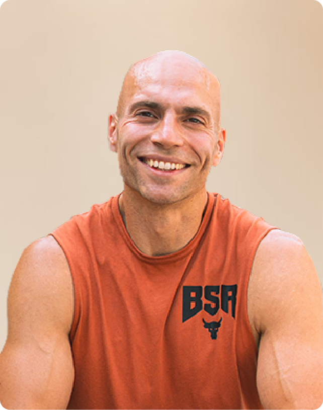 Smiling man in an orange sleeveless shirt with "BSA" logo, against a neutral background.